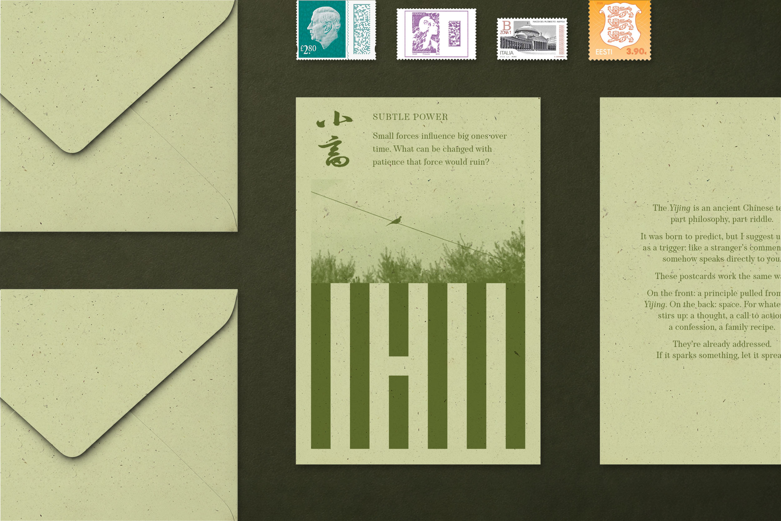 Flat-lay on dark green: a SUBTLE POWER postcard at the centre, showing the hexagram 小畜 and the line 'Small forces influence big ones over time. What can be changed with patience that force would ruin?' Two olive-paper envelopes sit on the left, four postage stamps along the top, and a printed sheet of the project manifesto on the right.